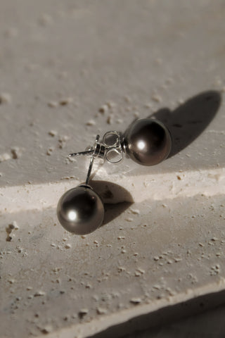 Pair of tahitian pearl studs on a textured surface