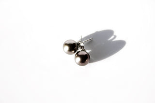 Pair of tahitian pearl studs on a white background.