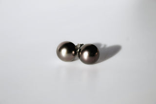 Pair of tahitian pearl studs on a light gray background