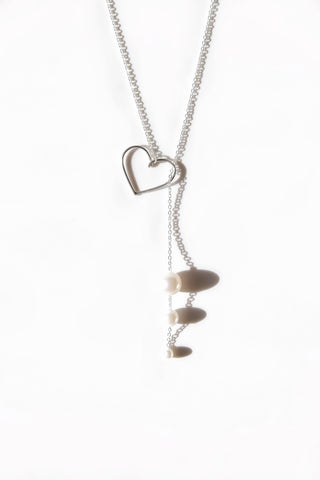 Silver lariat necklace with open heart pendant and three pearl drops over white background