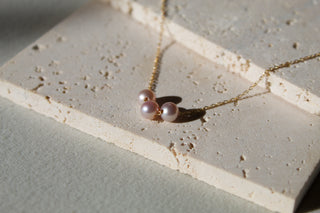 Three blush-pink freshwater pearl necklace on a gold chain.