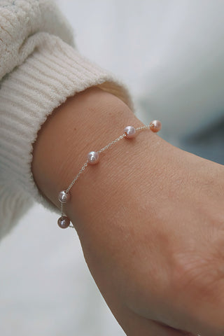 Silver pearl bracelet with blush-pink pearls being worn on a model's wrist. 